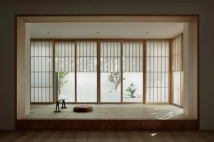 A modern interior with sliding wooden doors, plants, and a tatami mat.
