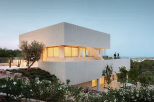 Modern minimalist white house with concrete exterior and large windows.