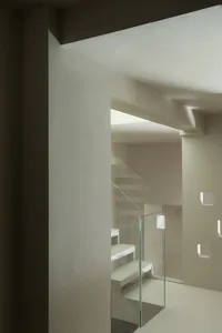 A modern minimalist staircase with glass railings and white concrete steps.