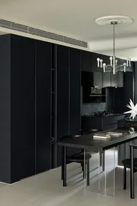 A modern kitchen with black cabinets and a long table.