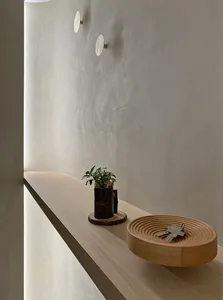 A minimalist wall shelf with a wooden bowl holding keys and a small plant pot.