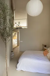 A minimalist bedroom with a concrete floor, a metal bed frame, and white textiles.