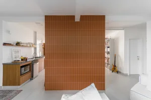 Modern residential kitchen with minimalist design featuring ceramic tiles on the floor and walls.