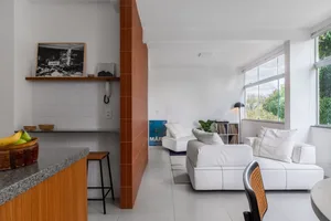 A modern living room with white furniture, a concrete floor, and a large window.