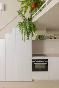 A modern minimalist kitchen featuring concrete cabinets and pendant plants.