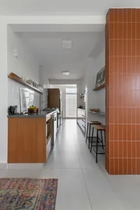 Modern industrial kitchen with white walls, wooden cabinets, and terracotta tiles.