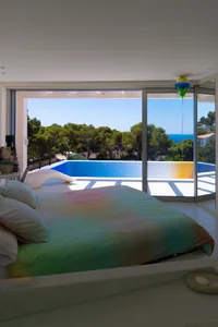 A minimalist bedroom with a modern bed and a colorful balloon outside the window.