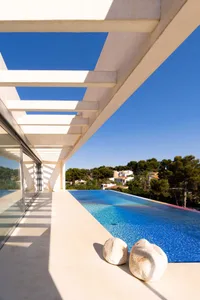 Concrete and glass minimalist terrace with an infinity pool overlooking a scenic landscape