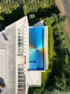 A modern outdoor swimming pool surrounded by greenery and glass.