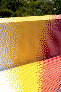 A modern swimming pool interior with a vibrant yellow, red, and white mosaic tile design.