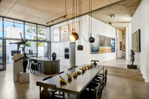 Minimalist dining and kitchen space featuring concrete flooring and walls.