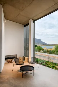 Minimalist outdoor terrace featuring concrete, wire-framed chairs and a circular coffee table.
