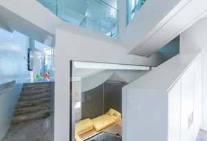 Modern living room featuring a glass-enclosed area with a yellow sofa.