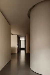 A minimalist interior with concrete walls, dark tiled flooring, and a curved pillar.