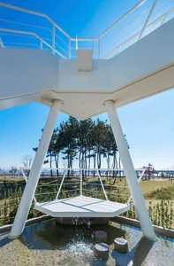 A minimalist metal public space with water features and a seating area.