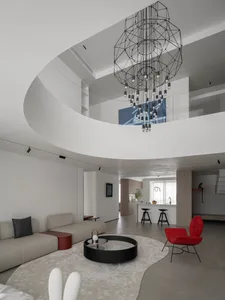 Modern living room with minimalist furniture, a geometric chandelier, and a round glass coffee table.