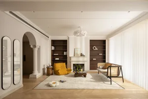 Modern living room with cushions on a wooden floor, leather armchair, and glass coffee table.