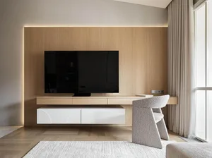 Modern minimalist living room with a flat-screen TV mounted on a wooden wall, a grey upholstered chair, wooden flooring, and
