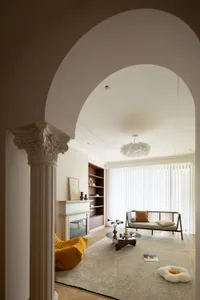 Modern living room with a neutral color palette, featuring a fireplace, a round coffee table, and a comfortable sofa.