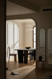Modern minimalist dining room featuring a wooden table and chair with a bowl of fruit on the table.