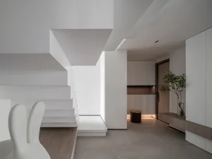 A modern minimalist living room with concrete flooring and wooden furniture