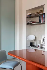 Minimalist dining room featuring a glass and metal table and light blue chair.