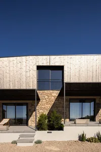 Modern residential exterior featuring minimalist design with wood cladding and stone foundation