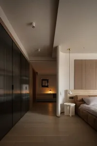 Modern bedroom featuring wooden flooring, sleek black wardrobe, and minimalist design elements.