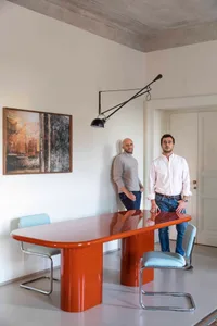 A modern interior design with concrete furniture, featuring a sleek orange desk and minimalist style.