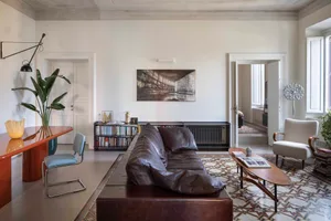 Modern living room featuring a black leather sofa, wooden coffee table, and a patterned tile floor.