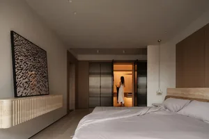 A minimalist bedroom with light-colored wooden furniture and stone accents.