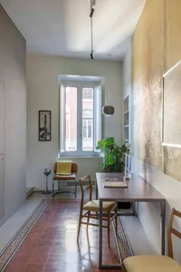 A minimalist, industrial-style office space featuring a modern metal desk, metal chairs, and a glass window.