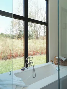 A minimalist bathroom featuring a large glass window overlooking a natural landscape.