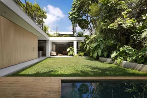 A modern backyard featuring lush greenery and a grassy area.