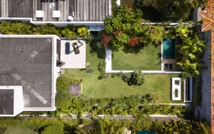 A modern backyard featuring a small pool surrounded by lush greenery and palm trees.