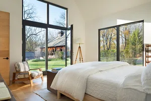 Modern, stylish bedroom with wooden furniture, large windows, and natural light