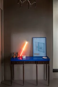A modern console table featuring a neon light and various decorative objects placed on top.