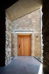 Modern entrance featuring a wooden door and stone walls