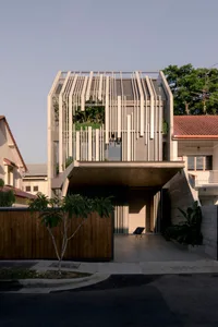 A modern house with a concrete and glass exterior, featuring a patio area with a chair.
