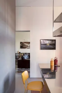A modern interior space featuring a living room with a leather sofa, bookshelves, and a glass table with decorative items.