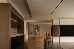 Modern kitchen featuring marble countertops and island, with minimalist design and sleek, dark wooden cabinets.