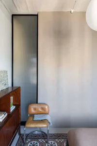 A modern minimalist interior with a concrete wall, brown leather chair, and tiled floor.