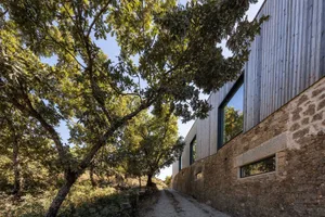 A modern residential building with a metal-clad exterior, surrounded by trees and natural surroundings.