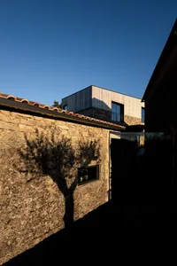 A stone house with a modern extension under a clear blue sky.