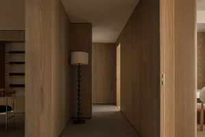 A minimalistic corridor with wooden walls and flooring, featuring a modern floor lamp.
