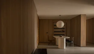 A minimalist dining room with wooden walls and furniture, featuring a round table with chairs.