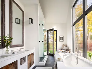 A modern bathroom featuring concrete elements, a large window, and a bathtub.