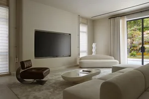 Modern, minimalist living room with sleek, white furniture and large television.