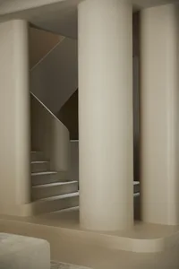 Modern, minimalist concrete staircase with sleek, cylindrical columns.