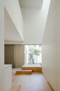 Modern residential hallway with white walls and wooden flooring.